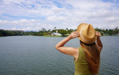 Holidays in Brazil. Young tourist woman on Pampulha Lake in Belo Horizonte, UNESCO World Heritage Site, Minas Gerais, Brazil. clipart