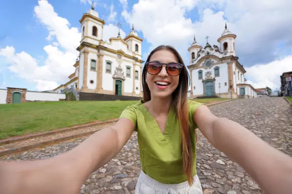 stock image Holidays in Minas Gerais, Brazil. Beautiful traveler girl takes selfie picture with smartphone in Mariana, Minas Gerais, Brazil.