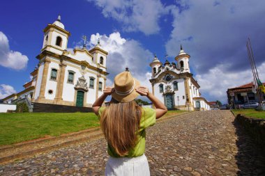 Tourism in Mariana, Minas Gerais, Brazil. Rear view of traveler woman visiting historical town of Mariana with baroque colonial architecture in Minas Gerais, Brazil. clipart