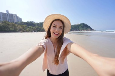 Brezilya sahillerinde selfie. Gülümseyen Brezilyalı kız Praia do Tombo Plajı 'nda kendi portresini çekiyor Guaruja, Sao Paulo, Brezilya.