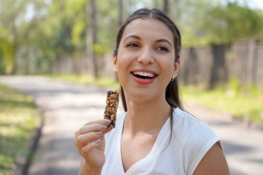 Açık havada elinde fındık gevreği olan genç bir kadının yakın çekimi.