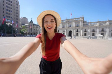 Santiago de Chile 'de turizm. Arka planda, Santiago, Şili 'de La Moneda Sarayı ile birlikte Plaza de la Constitucion' da gülümseyen genç turist kadının portresi..