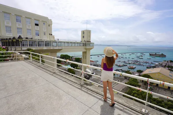 Brezilya, Salvador de Bahia 'da tatil. Brezilya 'nın Salvador de Bahia limanı ve Lacerda Asansörü' nün manzarasının keyfini çıkaran uzun boylu gezgin kız..
