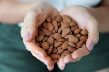 Badem soyulmamış. Kadın ellerinin soyulmamış bir yığın bademi tuttuğu yakın plan..