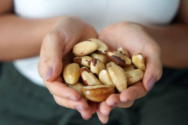 Brezilya fındığı. Bir avuç Brezilyalı fıstıkla yakın plan kadın eli..