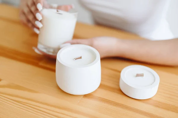 Place Under Label on Soy White Candles. Group of White Candles Stand on Wooden Table. Women's h\Hands with Ring Hold Candle Close-up.