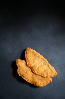 Karanlık bir arka planda Cheburek. Et ve soğanlı kızarmış turta. Geleneksel Türk, Moğol, Doğu Tatar, Kafkas mutfağı. Yukarıdan bak. Boşluğu kopyala.