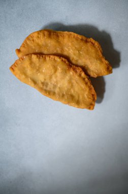 Hafif arka planda Cheburek. Et ve soğanlı kızarmış turta. Geleneksel Türk, Moğol, Doğu Tatar, Kafkas mutfağı. Yukarıdan bak. Boşluğu kopyala.