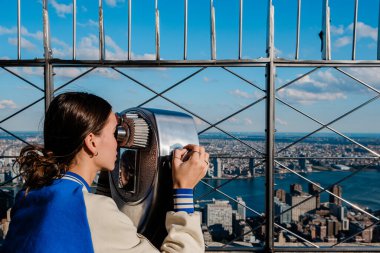 Empire State Binası 'ndan dürbünle Manhattan ufuk çizgisine bakan genç bir kız. Yüksek kalite fotoğraf