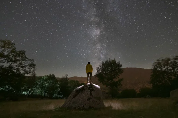 Vue Arrière Homme Grimpé Sur Rocher Regardant Voie Lactée Nuit Image En Vente