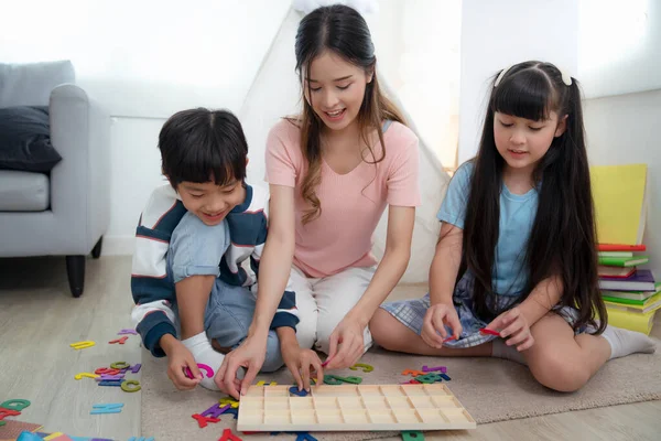 亚洲母亲和她的女儿一起在客厅里玩耍和学习 他们一起玩文字游戏 — 图库照片