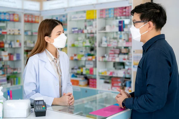 薬局の保護マスクを持つアジアの薬剤師の女性彼女の顧客と薬や薬局を販売するための彼女のビジネスの店 — ストック写真