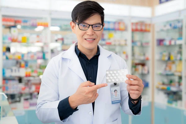 アジア人薬剤師の男性は薬局で彼の顧客に薬と薬を使用する方法を説明します — ストック写真