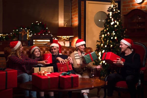 アメリカの家族のメリークリスマスと新年のパーティーはギフトボックス付きの自宅でソファに座って 家族は家で作る七面鳥のグリルダイニングトークアップを楽しむ — ストック写真