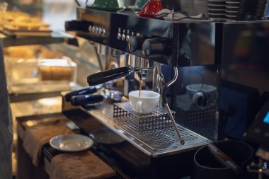 Women barista in an apron making coffee with coffee maker machine in a coffee shop