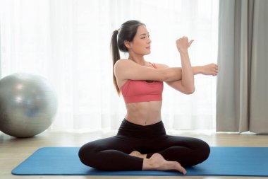 Asyalı kadın yatak odasında egzersiz yapıyor ve esniyor. Yoga, kardiyo ve karantina arasında evde spor yaparak zayıflamaya çalışıyor.