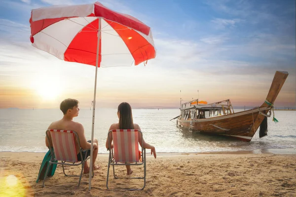 アジアの旅行者のカップルは座って夕日がビーチに集まり タイのプーケット近くのピピ島マヤビーチでロングテールボートの背景 — ストック写真