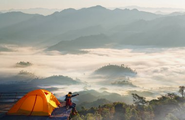 Asyalı çift kamp noktalarında çadırlarının keyfini çıkarıyorlar. Sabah güneş ışığı, sis ve dağ manzarası, Tak 'taki Doi mon kalakojo manzarası, Tayland, Chiang Mai yakınlarında.