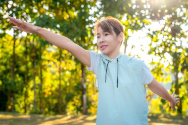 Orta yaşlı Asyalı kadın spor giyim tarzında parkta yoga ve sabah vakti yeşil doğa. 