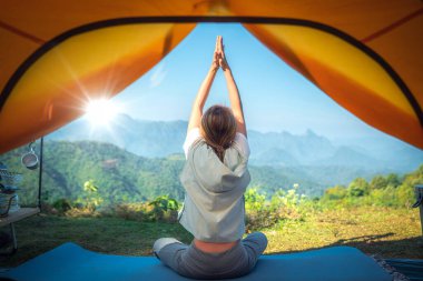 Asyalı gezgin kadın Tayland 'da dağ ve açık hava geçmişiyle birlikte çadırına yoga yapıyor. 