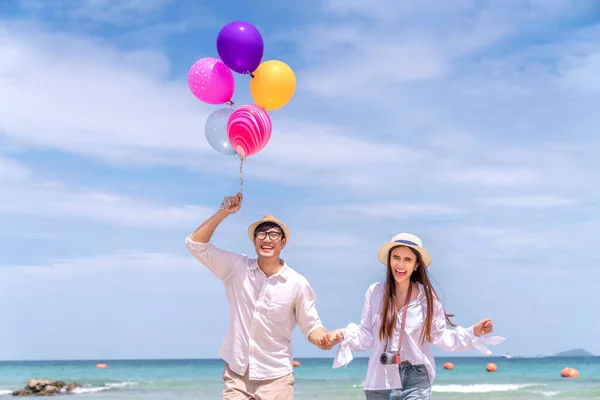在暑假期间 一对亚洲夫妇在泰国海滩观光 并在海滩上气球 — 图库照片