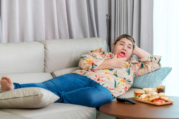 Asian over size fat woman enjoy over eating on the living room, un healthy foods and junk food concept photo
