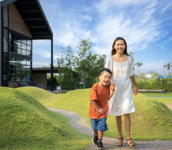 亚洲的母亲和她的小儿子跑到花园里用绿草聚集在一起 — 图库照片