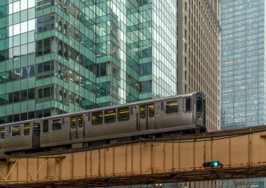 Binalar arasındaki Loop, Glass and Steel köprüsündeki yüksek raylarda tren, Chicago City Center, Chicago, Illinois, ABD