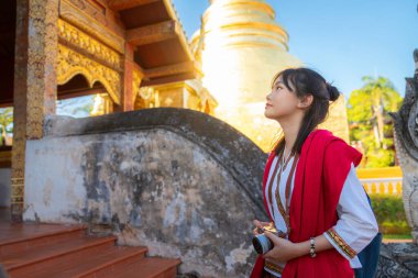 Asyalı kadın gezgin. Geleneksel olmayan kırmızı elbise. Chiang Mai şehrindeki eski tapınakta seyahat ediyor.