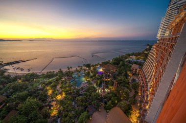 Pattaya Sahili 'nin şehir manzarası ve otel çatısı, günbatımı gökyüzü ve deniz manzarası ve aşağıdaki park yeri, Tayland' da Bangkok yakınlarındaki tropikal tatil köyü.