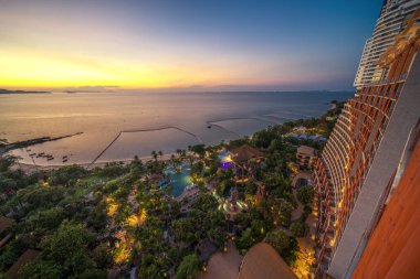 Cityscape of pattaya beach and city from hotel rooftop with sunset sky and sea view and park below, tropical resort in Thailand near Bangkok clipart