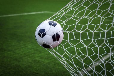 Top kalede net arka planda, futbolcu sayı yapmak için deri bir ayak topu atıyor.