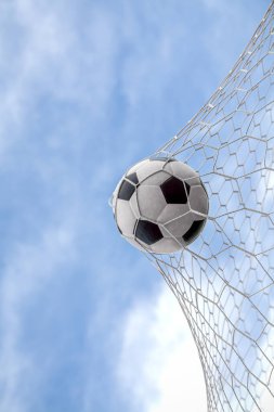 Top kalede net arka planda, futbolcu sayı yapmak için deri bir ayak topu atıyor.