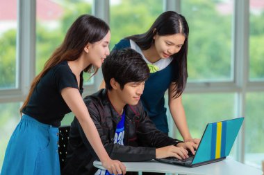 Ev ödevi yapan Asyalı öğrenci üniversitede kütüphanede bir araya geliyor, takım çalışanları bilgisayar defteriyle buluşuyor.