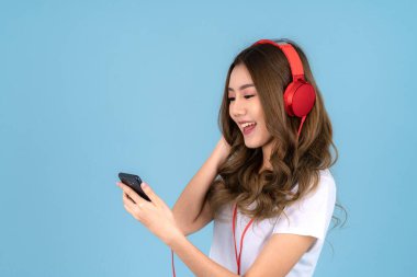 Mutlu Asyalı kadın, arka planda kulaklığı ve akıllı telefonu olan bir şarkı söylüyor.