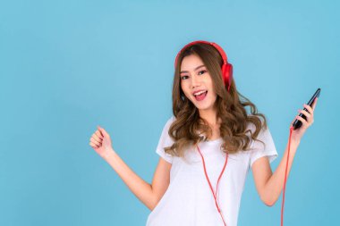 Mutlu Asyalı kadın, arka planda kulaklığı ve akıllı telefonu olan bir şarkı söylüyor.