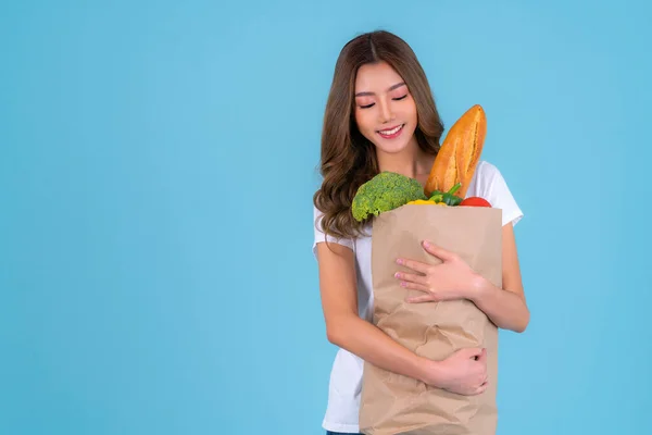Asian woman carry paper shopping bag from supermarket with  vegetables inside a bag with isolated background