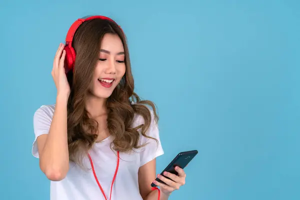 Happy asian woman sing a song with headphones and smartphone on her hand on the isolated background