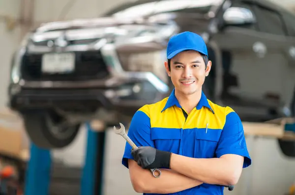 repairman and technician in car garage service in blue uniform standup and smile with tooling on hand for car check and maintenance