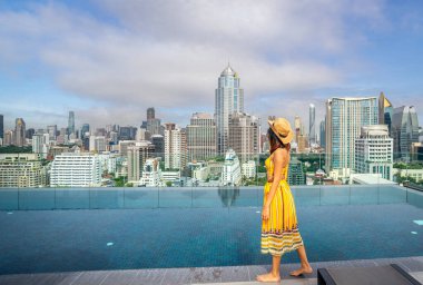 Asyalı gezgin kadın Bangkok, Tayland manzaralı otelin çatısındaki havuzda uyuyor ve dinleniyor.