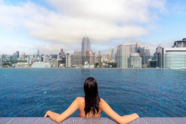 Asyalı gezgin kadın Bangkok, Tayland manzaralı otelin çatısındaki havuzda uyuyor ve dinleniyor.