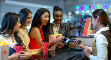 Asyalı bir kadının mutlu arkadaş grubu sakin olun ve Cimema sinemasına birlikte gidin ve bilet ve satış reyonunda patlamış mısır alın.