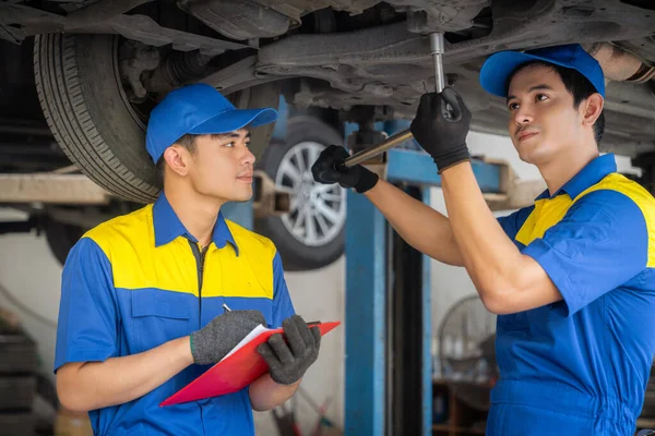 repairman and technician in car garage service in blue uniform standup and smile with tooling on hand for car check and maintenance