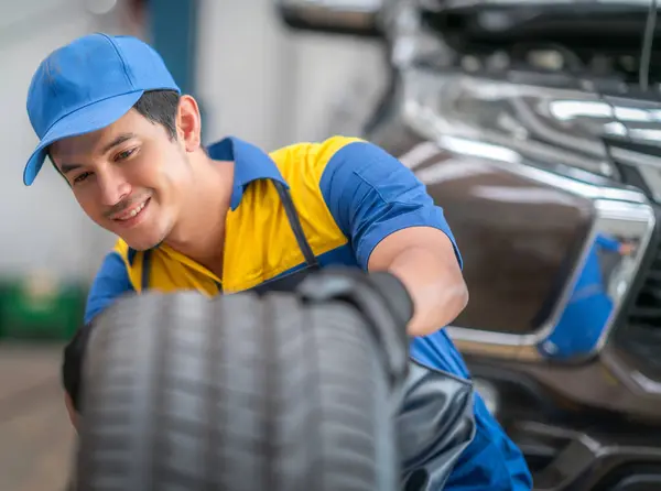 repairman and technician in car garage service in blue uniform standup and smile with tooling on hand for car check with car owner