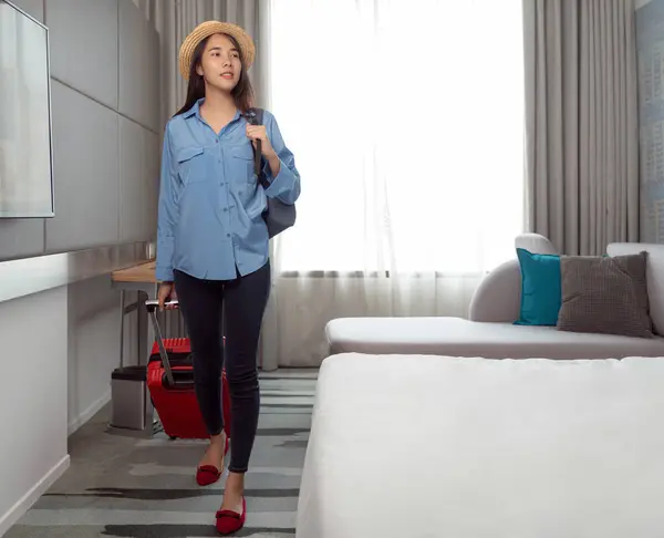 Asian traveller woman take travel bag and walking check out from her hotel room after finish her travel trip