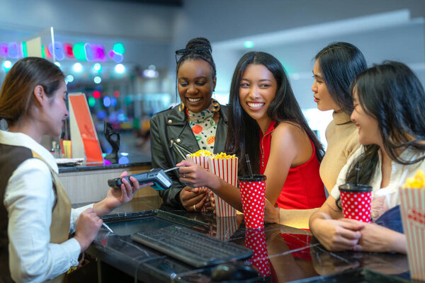 Happy group of friends of asian woman relax and go to Cimema in movie theater together and buy ticket and popcorn in sales counter service