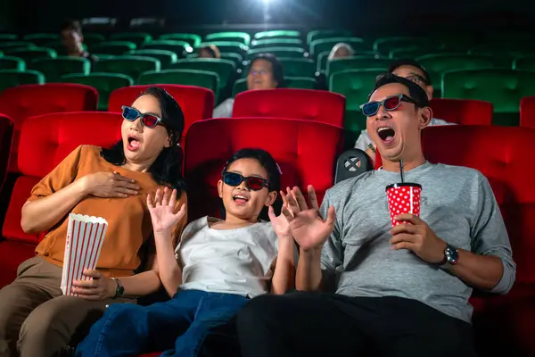 Asian family relax and fun togather by watching 3d action cinema in theater, father mother and daughter holiday in weekend with action movie