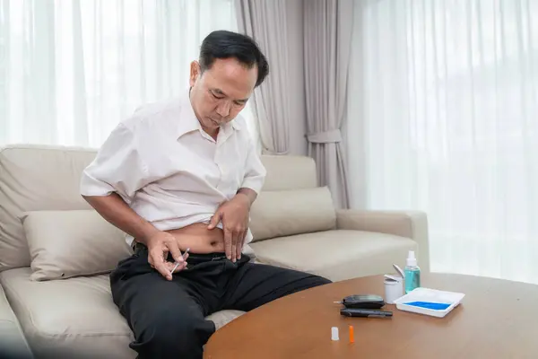 Asiatischer Alter Mann Checkt Selbst Hause Einen Zuckerspiegel Blut Insulin lizenzfreie Stockbilder