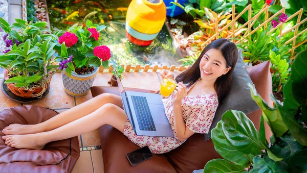 在家里的花园里 亚洲女人在咖啡店里睡觉和放松 在家里带着电脑笔记本 在度假胜地带着绿色的天性 免版税图库照片