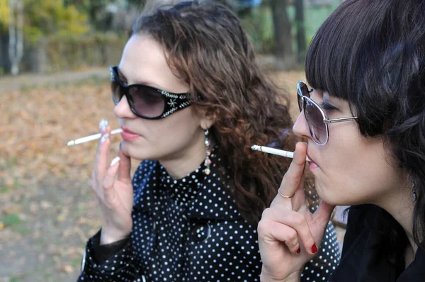 Duas Jovens Mulheres Relaxando Parque Outono Fumando Cigarros — Fotografia de Stock